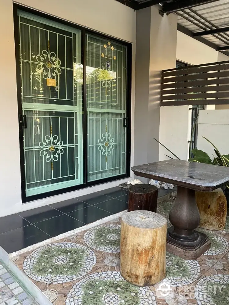 Charming patio with rustic seating and decorative metal door in cozy outdoor space.