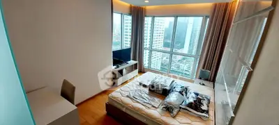 Modern bedroom with large windows offering stunning city views in a high-rise apartment.