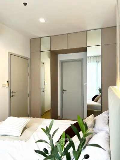 Modern bedroom with stylish decor and mirrored wardrobe doors