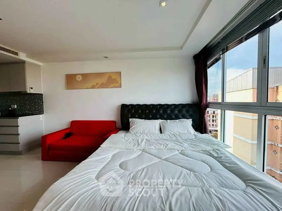 Modern bedroom with large window and red sofa in stylish apartment
