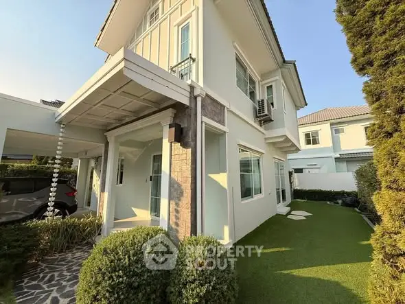 Charming two-story house with manicured garden and carport in a serene neighborhood.