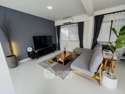 Modern living room with sleek furniture and large TV, featuring stylish decor and natural light.