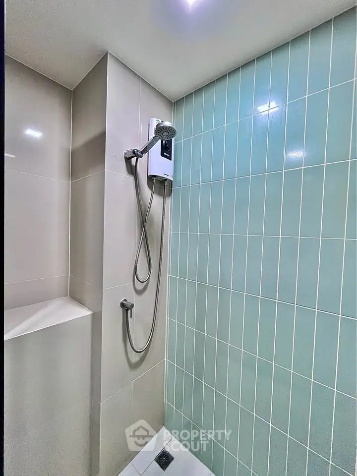 Modern bathroom shower area with sleek tiles and built-in shower unit.