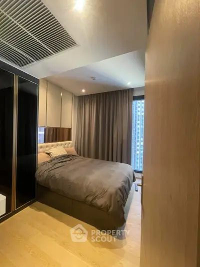 Modern bedroom with cozy ambiance and city view, featuring elegant decor and ample natural light.