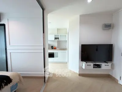 Modern apartment interior with sleek kitchen and cozy living area, featuring a wall-mounted TV and stylish decor.