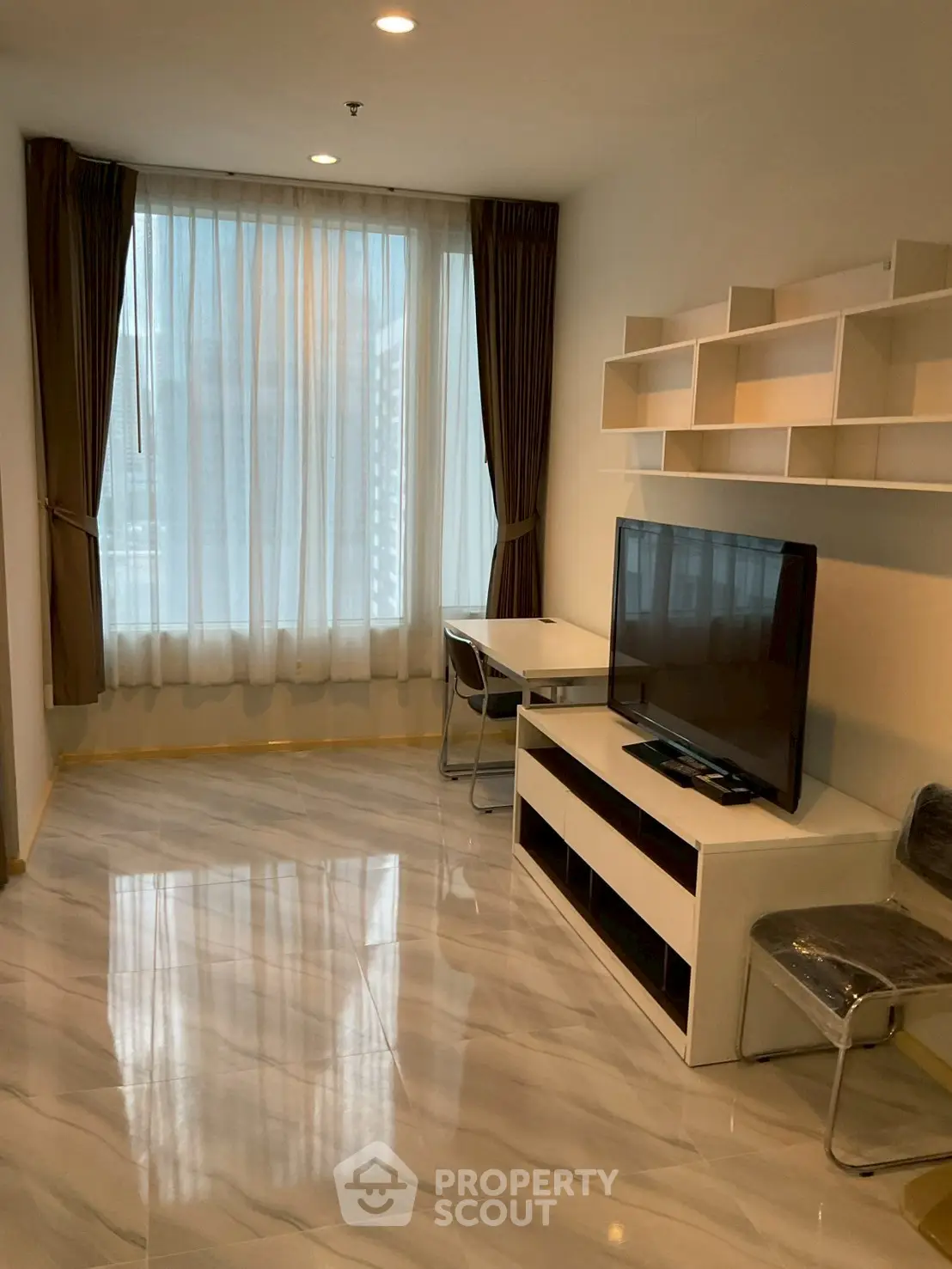 Modern living room with sleek flooring and large window, featuring a TV and stylish shelving.