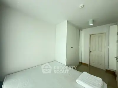 Spacious minimalist bedroom with white walls and built-in wardrobe, perfect for modern living.