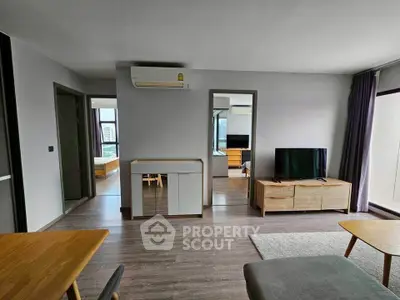 Modern living room with wooden furniture and large windows offering city views.