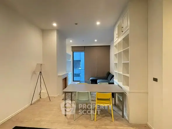 Modern living room with dining area and built-in shelves, featuring stylish lighting and cozy seating.