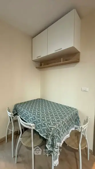 Cozy dining nook with patterned tablecloth and modern chairs under sleek wall cabinets.
