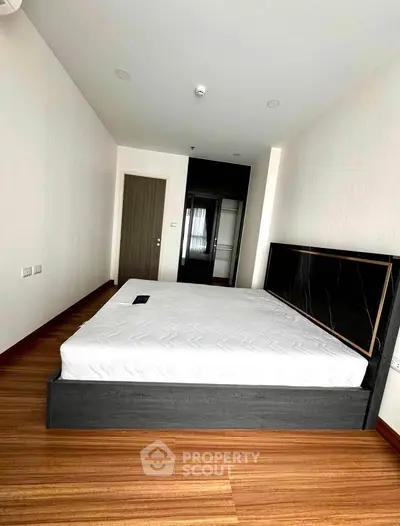 Modern bedroom with sleek wooden flooring and stylish bed frame in a contemporary apartment.