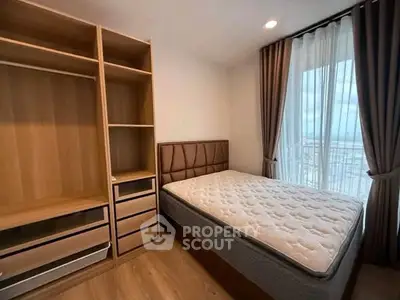 Modern bedroom with large window and built-in wardrobe, offering ample natural light and storage space.