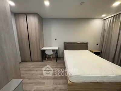 Modern bedroom with minimalist design, featuring a comfortable bed, sleek wardrobe, and study desk.