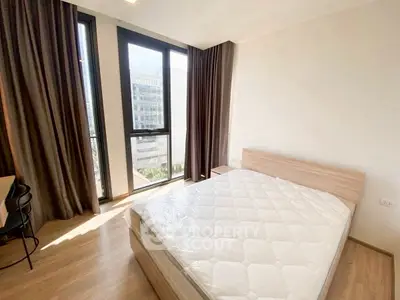 Bright bedroom with large windows and modern furnishings in a high-rise apartment.