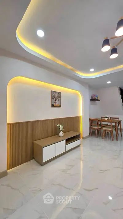 Modern living room with stylish lighting and dining area, featuring sleek furniture and elegant decor.