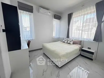 Modern bedroom with large windows, sleek furnishings, and natural light.