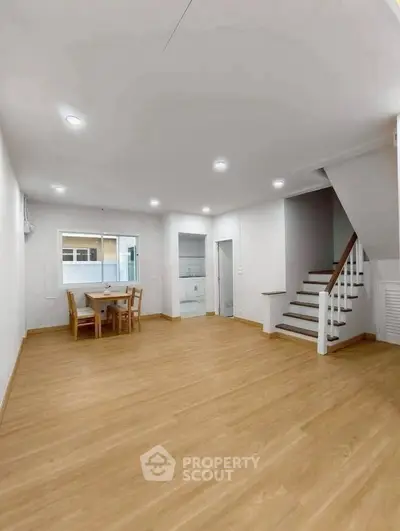 Spacious open-plan living area with wooden flooring and staircase, ideal for modern family living.