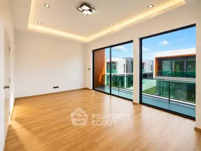 Spacious modern living room with large windows and wooden flooring, offering a bright and airy atmosphere.