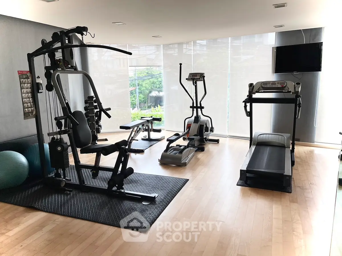Modern gym with exercise equipment and large windows in a residential building.