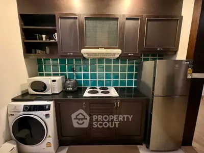 Modern kitchen with dark wood cabinets, stainless steel fridge, and washing machine.