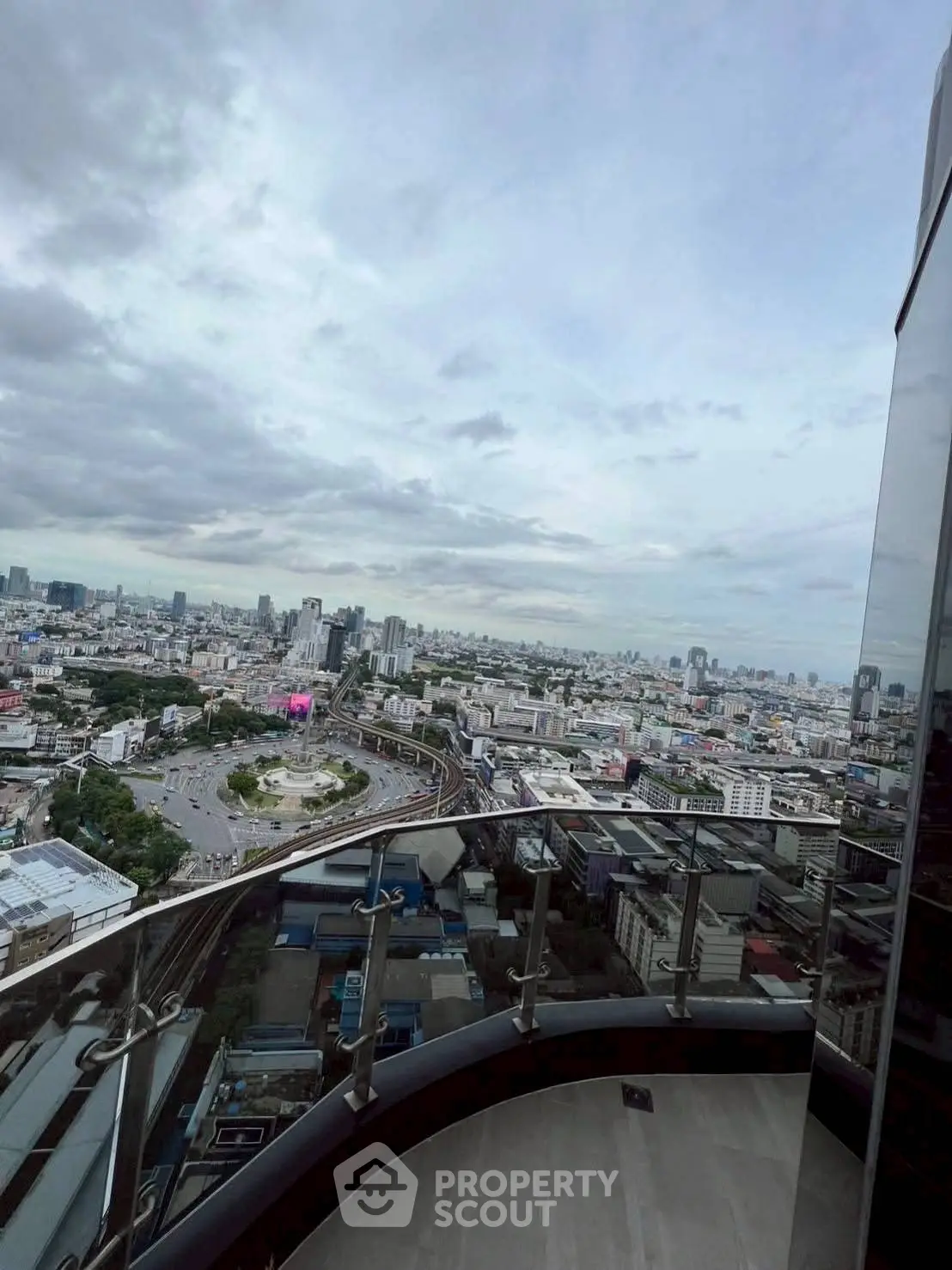Stunning cityscape view from a high-rise balcony with sleek glass railing.