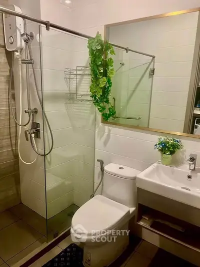 Modern bathroom with glass shower, white sink, and decorative plants for a fresh look.