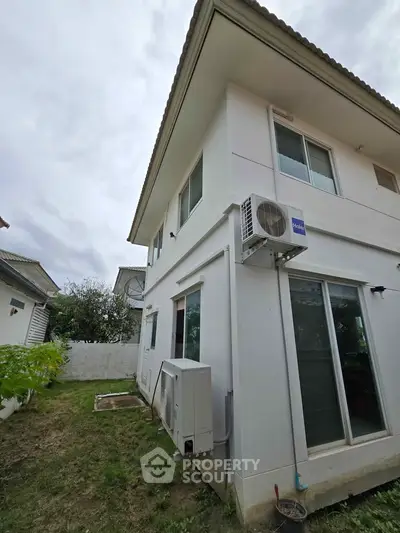 Modern two-story house exterior with air conditioning units and sliding glass doors.