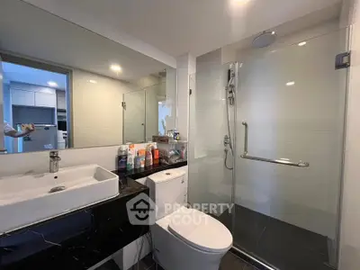 Modern bathroom with sleek fixtures and glass shower enclosure in a contemporary apartment.