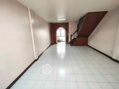 Spacious open-plan living area with tiled flooring and staircase, ideal for modern living.