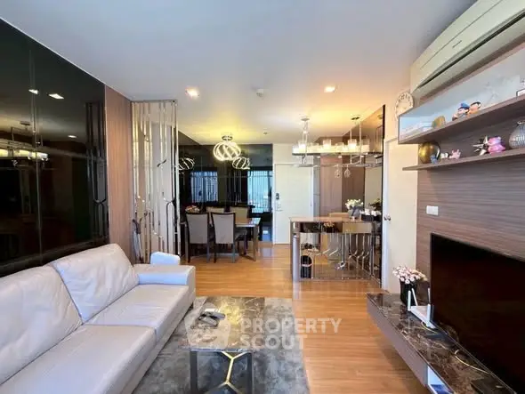 Modern living room with elegant decor and open dining area, featuring stylish lighting and wooden flooring.