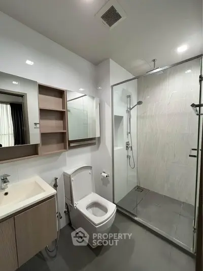 Modern bathroom with glass shower and sleek fixtures in contemporary apartment.