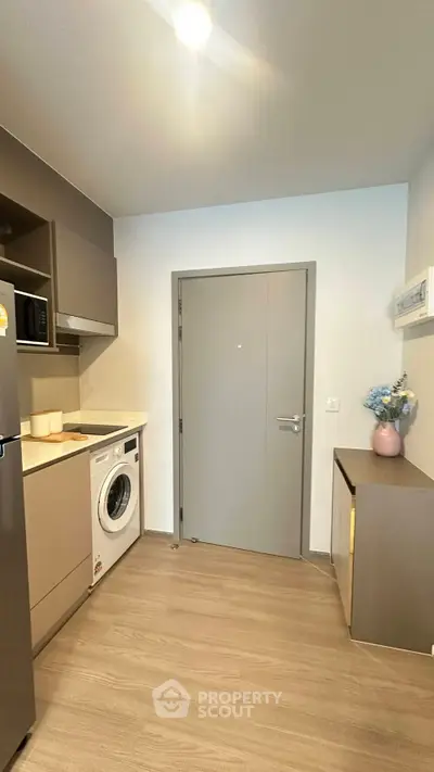 Modern kitchen with washing machine and sleek cabinetry in compact layout.