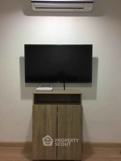 Modern living room with wall-mounted TV and sleek wooden cabinet