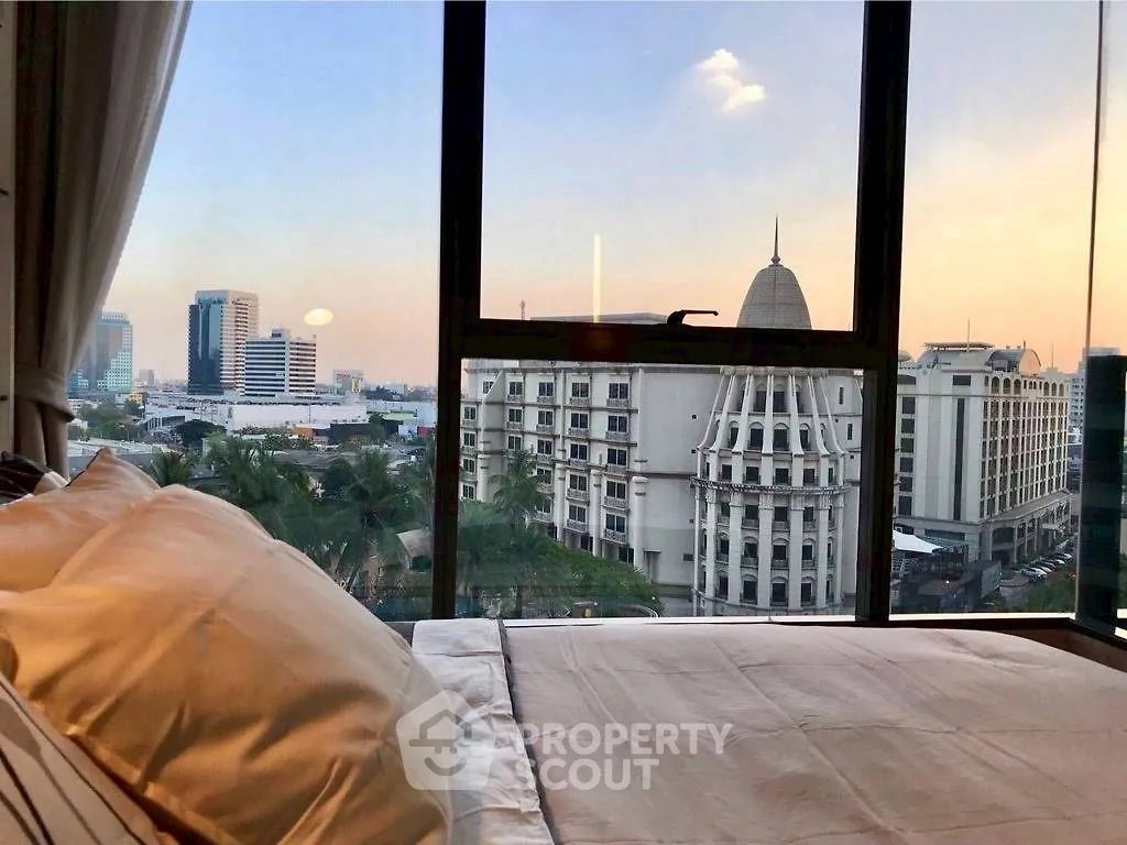 Luxurious bedroom with stunning city view from large windows, offering a serene urban living experience.