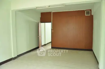 Spacious empty room with wooden accent wall and open doorway