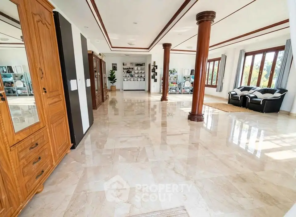 Spacious and elegant living room with marble flooring and large windows offering natural light.