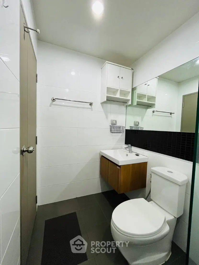 Modern bathroom with sleek fixtures and minimalist design, featuring a wall-mounted sink and spacious mirror.