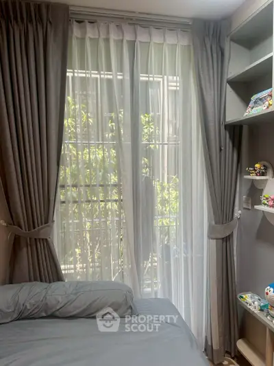 Cozy bedroom with elegant curtains and a view of lush greenery, perfect for relaxation and tranquility.