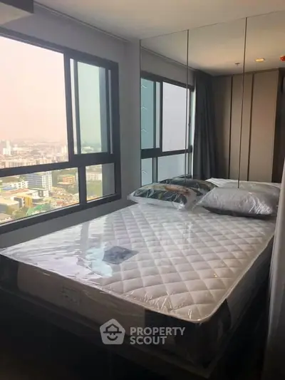 Modern bedroom with large windows offering stunning city views, featuring a comfortable bed and mirrored wall.