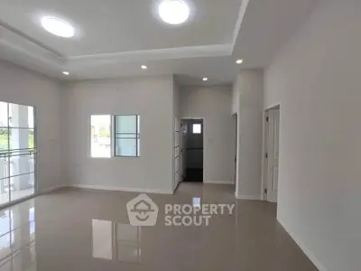 Spacious modern living room with large windows and sleek tile flooring.