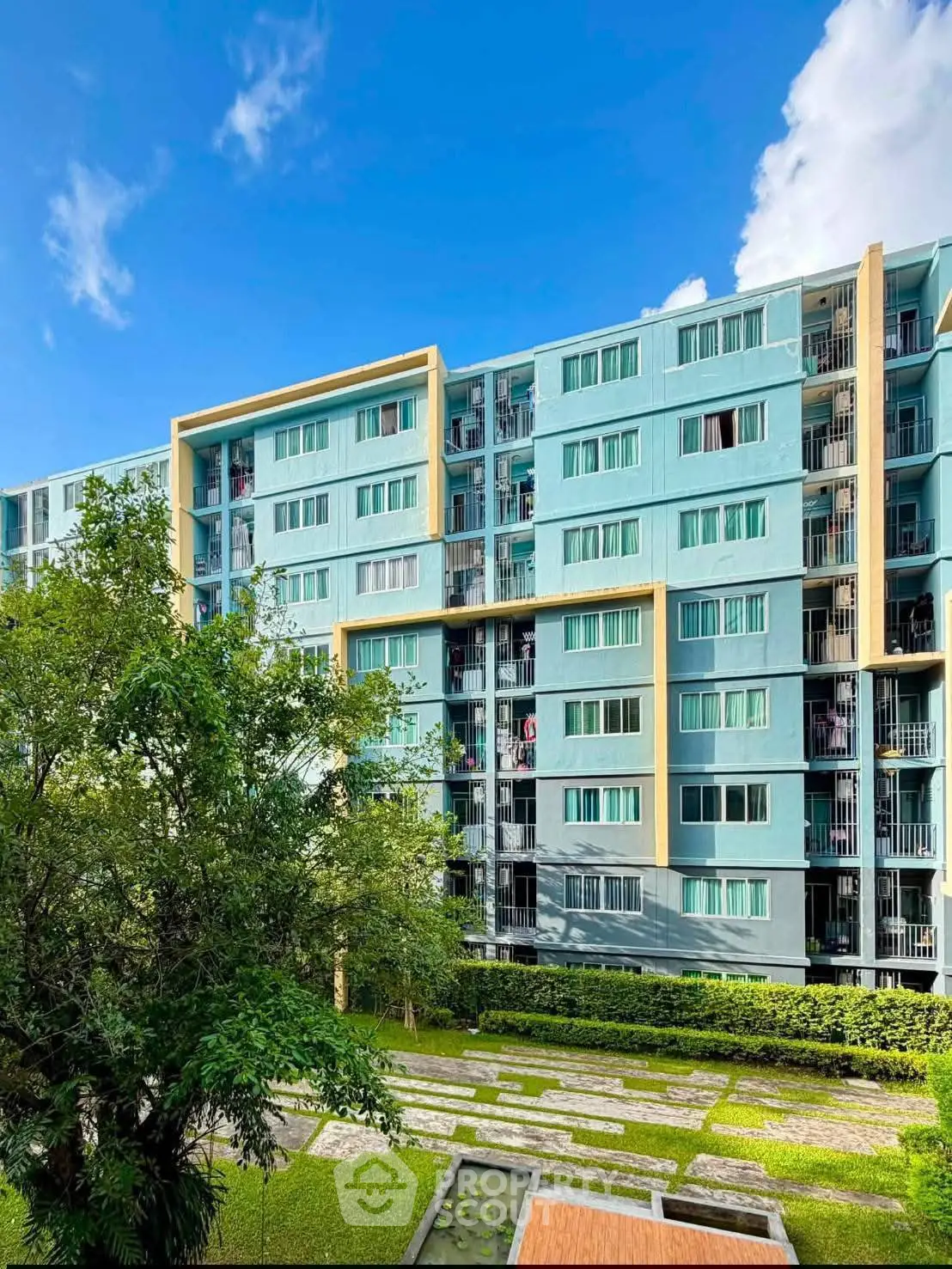 Modern residential building with lush green surroundings and clear blue sky.