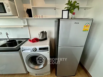 Modern kitchen with washing machine, fridge, and microwave in compact layout.