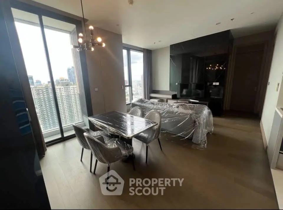 Modern living room with floor-to-ceiling windows and city view, featuring elegant dining area and stylish lighting.