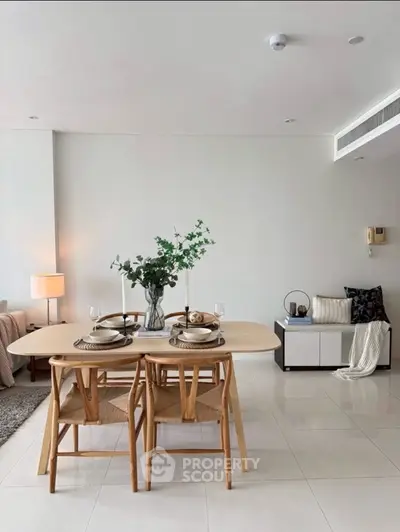 Modern dining area with elegant table setting and cozy seating in a stylish open-plan living space.