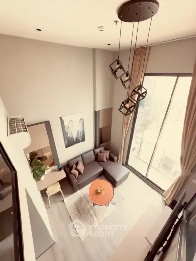 Modern loft-style living room with high ceiling and large windows offering city views.