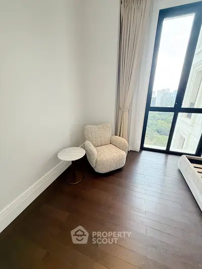 Cozy corner with plush armchair and side table overlooking scenic city view.