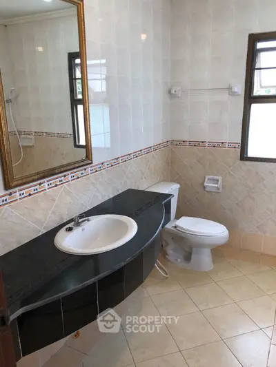 Spacious bathroom with elegant sink and modern fixtures, featuring large windows for natural light.