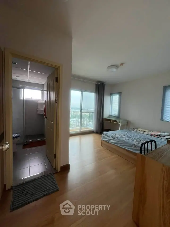 Spacious bedroom with balcony view and attached bathroom in modern apartment.
