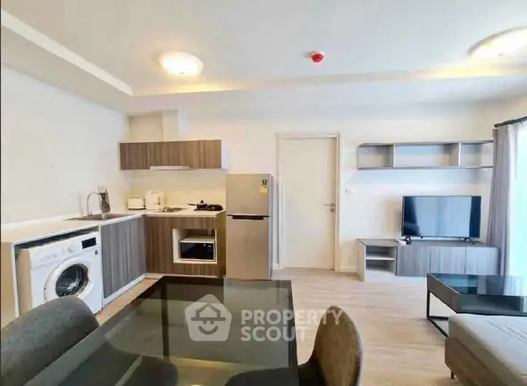 Modern open-plan living room with kitchen, dining area, and appliances in a stylish apartment.
