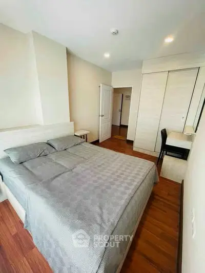 Modern bedroom with wooden flooring and built-in wardrobe in a cozy apartment.